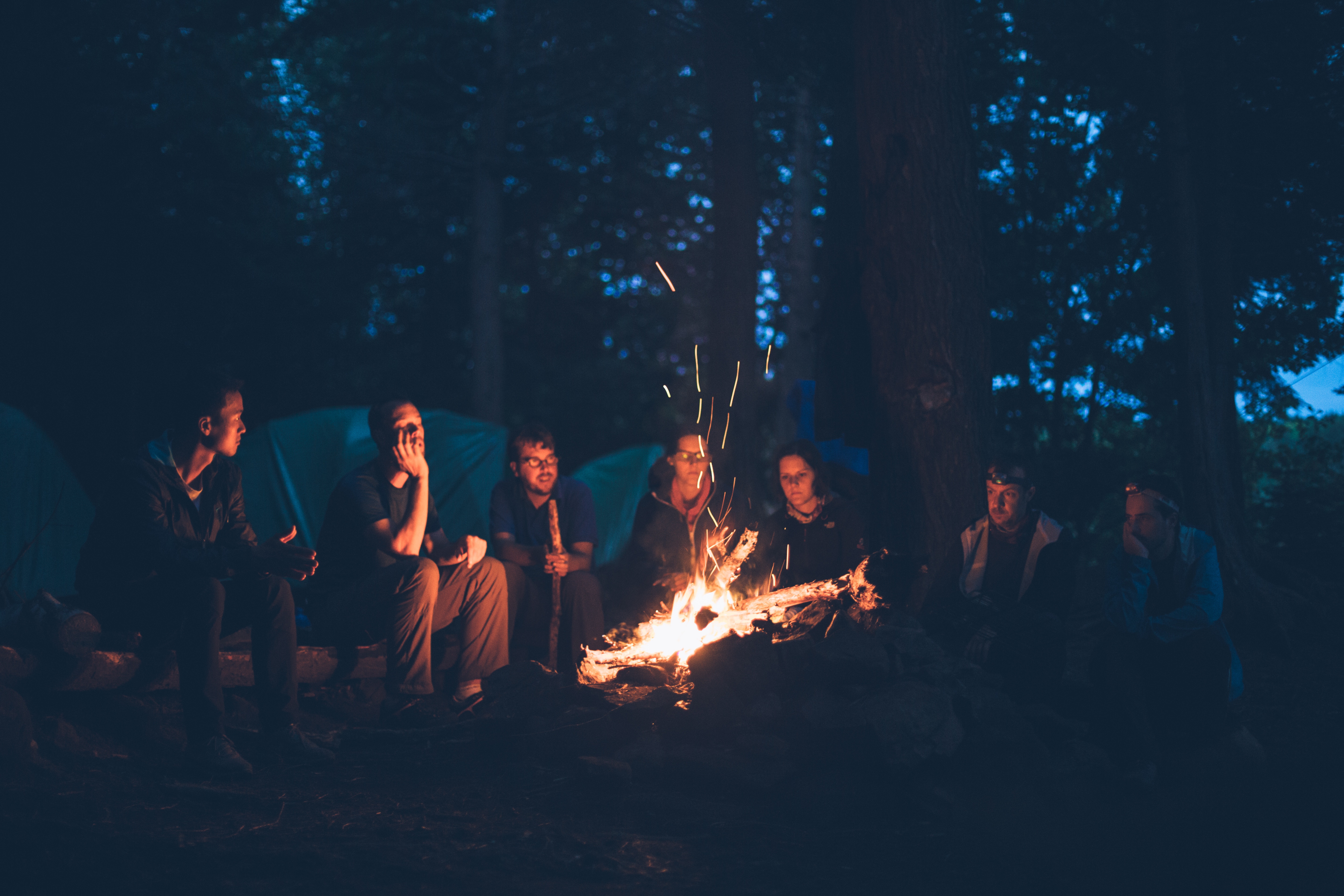 A group of people, laughing around a campfire